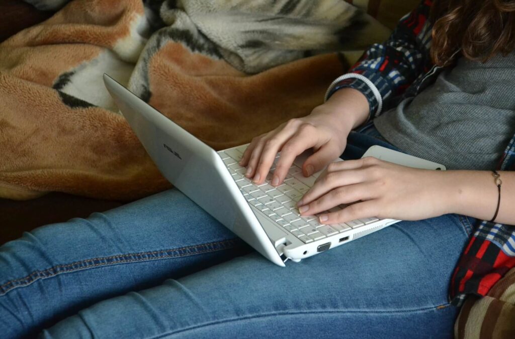 膝の上でパソコンを触る女性
